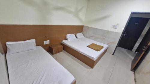a small room with two beds and a mirror at RK Hotel in Boisar