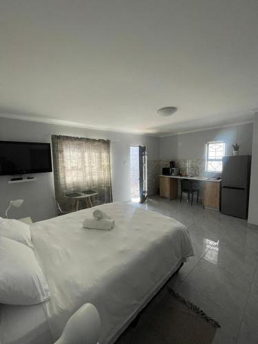 a bedroom with a large white bed and a kitchen at Eighth Avenue Self Catering Accommodation in Lüderitz