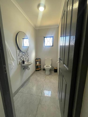 a bathroom with a toilet and a sink and a mirror at Eighth Avenue Self Catering Accommodation in Lüderitz