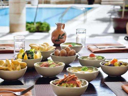 a table topped with bowls of food on a table at Mövenpick Resort Petra in Wadi Musa