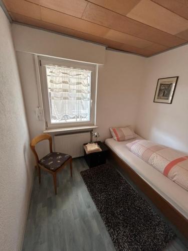a bedroom with a bed and a window and a chair at Apartment am Rathaus 3SZ in Rödermark