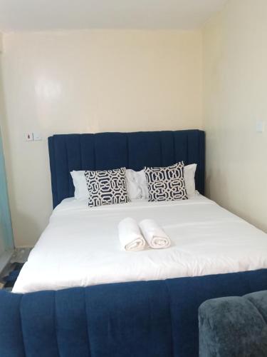 a bed with a blue headboard and two slippers on it at AA Suites 87 in Nairobi
