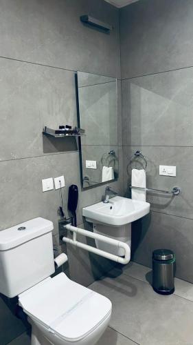 ein Badezimmer mit weißer Toilette und Waschbecken in der Unterkunft Kaloor Residency in Ernakulam