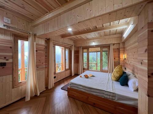 a wooden cabin with a bed in a room with windows at The nature view A shape tree cottage in Banjār