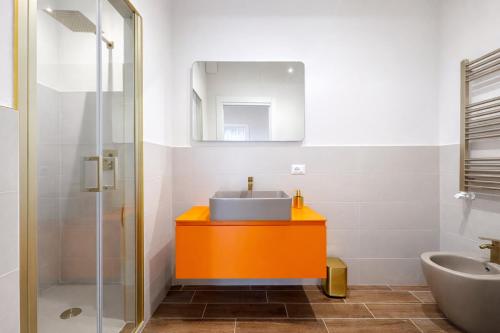 ein Badezimmer mit einem orangenen Waschbecken und einem Spiegel in der Unterkunft Maison Hermes in Mailand