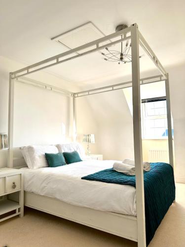 a bedroom with a white canopy bed with blue pillows at Spacious 5-Bed Detached House, Sleeps 10, Parking in Desborough