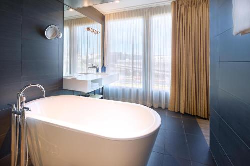 a bathroom with a tub and a sink and a mirror at Radisson Blu Hotel, Lucerne in Lucerne