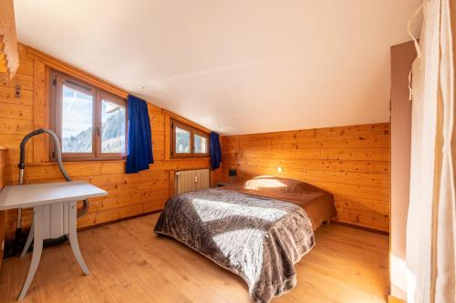 een slaapkamer met een bed in een kamer met houten wanden bij Le petit Schuss in La Giettaz