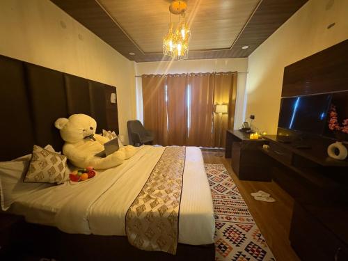 un orsacchiotto seduto su un letto in una camera d'albergo di The Blue Park By OSCAR a Manāli