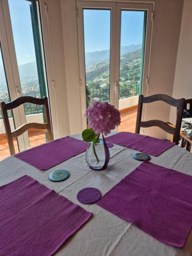 a table with a vase with purple flowers on it at Apartamento Charmoso no Funchal, com grande Jardim e Vista Esplêndida in Funchal