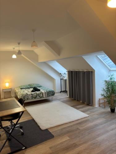 a room with a bed and a desk in a attic at Appartement spacieux et élégant in Laon