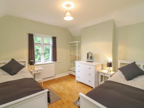 a bedroom with two beds and a dresser and a window at School House in Ivybridge