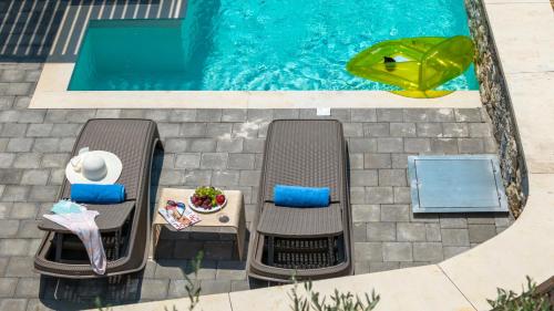 an overhead view of two lounge chairs and a pool at Pasithea Villas in Neokhórion