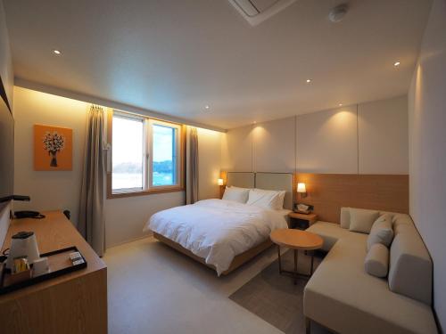 una camera d'albergo con un letto e un divano di Daisy hotel a Tongyeong