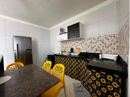 a kitchen with a table and chairs and a refrigerator at AP Brisa do Rio in Galinhos