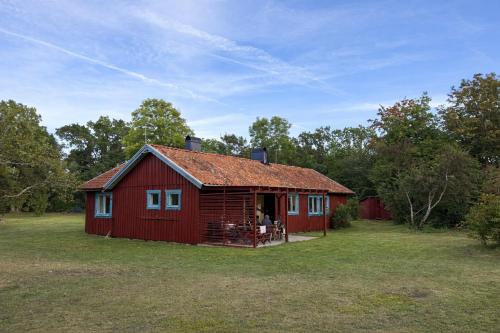 un fienile rosso con una persona seduta sulla soglia di Djupvik - Oland's sunny coast a Borgholm