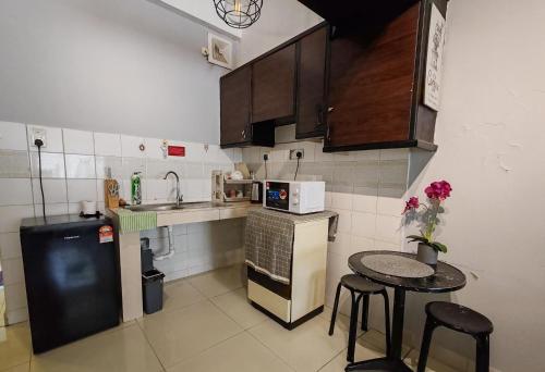 una piccola cucina con un tavolo e un frigorifero di KK City Centre Api Api Apartment a Kota Kinabalu