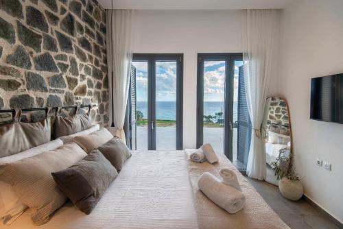 a large bed in a room with a stone wall at KYAN Syros in Liaropá