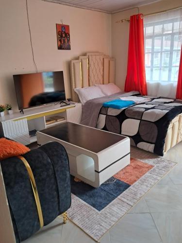 a living room with two beds and a tv at Watene's Homes in Nairobi