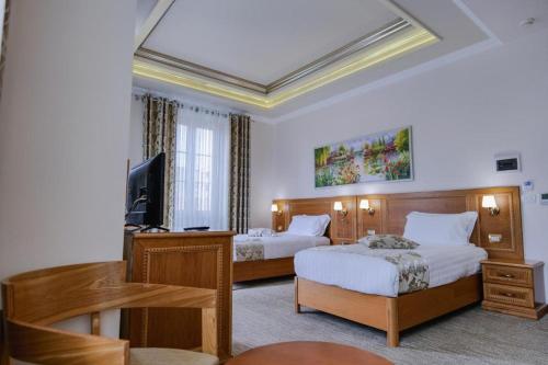 a hotel room with two beds and a flat screen tv at HOTEL BOCA Center in Tirana