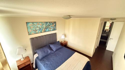 een slaapkamer met een blauw bed en een schilderij aan de muur bij Viña del Mar - Parque Marina in Viña del Mar