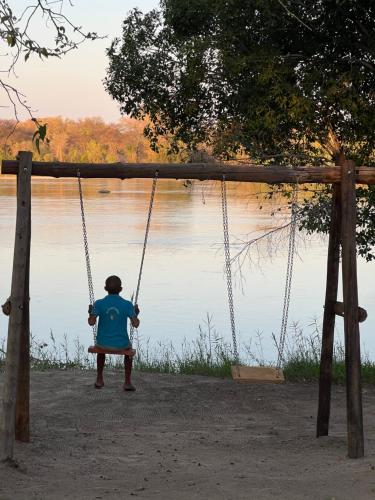 een persoon op een schommel bij een meer bij Edsam Lodge in Divundu