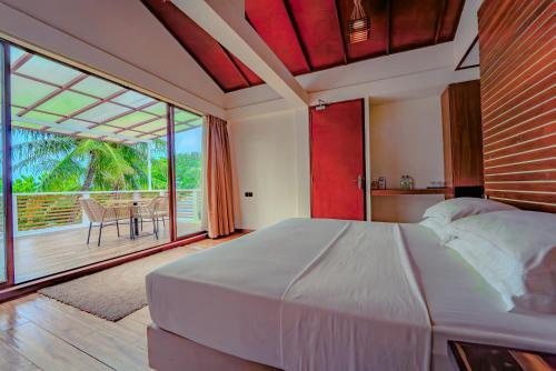 een slaapkamer met een groot bed en een balkon bij Kinan Retreat in Fulidhoo
