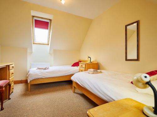 a bedroom with two beds and a mirror at Hazel Lodge in Blairgowrie