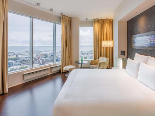 ein Hotelzimmer mit einem großen Bett und großen Fenstern in der Unterkunft Swissotel Tallinn in Tallinn