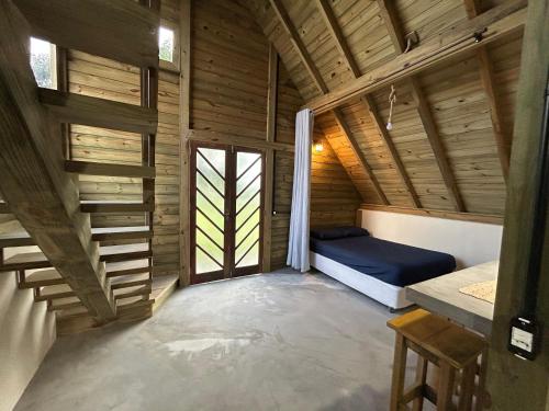 a small room with a bed in a wooden house at pousada Aroeira, G Embaú in Palhoça
