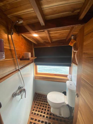 a small bathroom with a toilet and a window at Shared Boat Komodo 3 days 2 Night in Komodo Labuan Bajo Airport