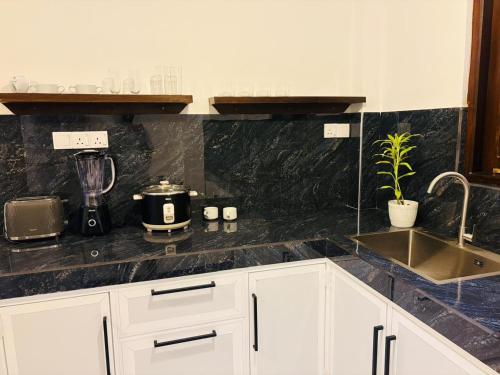 a kitchen with white cabinets and a black counter top at Sea Breeze Heaven in Tangalle