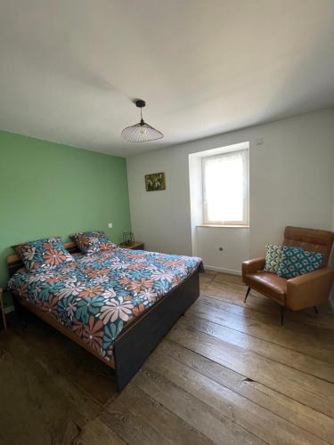 a bedroom with a bed and a chair and a window at La Flore in Baraqueville
