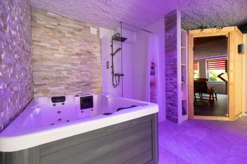 eine große Badewanne im Badezimmer mit violetter Beleuchtung in der Unterkunft Pension Schlossidyll in Wernigerode