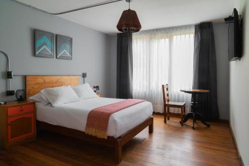 a bedroom with a bed and a table and a window at qema Arequipa in Arequipa