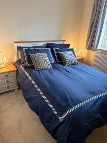 a blue bed with pillows on it in a bedroom at Hatters Cottage Eldwick Bingley Yorkshire in Bingley