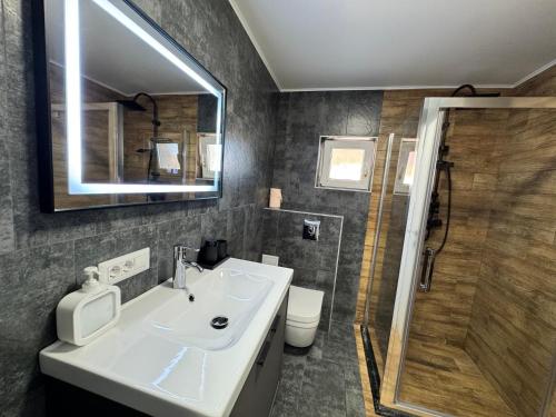 a bathroom with a sink and a shower and a mirror at V apartament - ultra central Otopeni in Otopeni