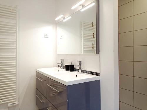 a white bathroom with a sink and a mirror at La Filature in Rochesson