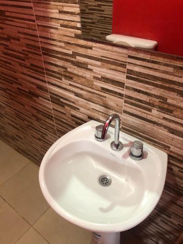 a white sink in a bathroom with a red wall at Casa privada en Maimara in Maimará