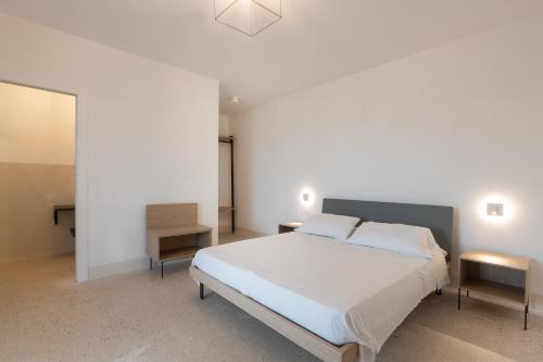 a bedroom with a large white bed and two tables at Masseria l'Ulìa in Gallipoli