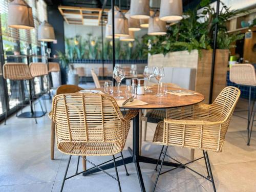 een houten tafel met stoelen en wijnglazen erop bij Ibis Lunel Petite Camargue in Lunel