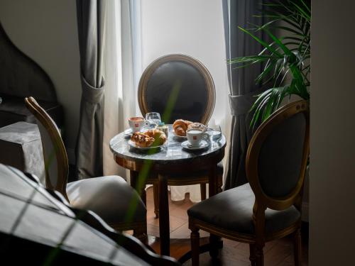 ein Tisch mit einem Tablett mit Gebäck darauf und zwei Stühlen in der Unterkunft Locanda Sibilla Luxury Suites in Tivoli