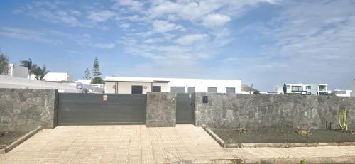a black fence with a stone wall in front of a house at Villa Mare in Teguise