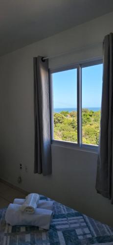 a bedroom with a bed and a window with a view at Apartamento em Imbituba in Imbituba