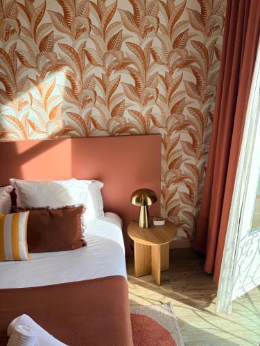 a bedroom with a bed and a wall with a wallpaper at Hôtel De Londres in Menton