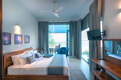 a bedroom with a large bed and a large window at Mawakada Bay Residences in Hikkaduwa