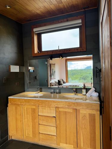 a bathroom with two sinks and a window at NÓMADES Hotel Boutique in Coihaique