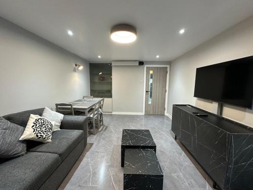 a living room with a couch and a flat screen tv at Modern, comfortable flat close to transport hubs in Stockport