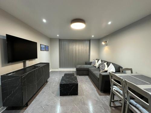 a living room with a couch and a flat screen tv at Modern, comfortable flat close to transport hubs in Stockport