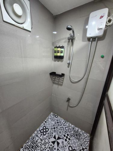 a bathroom with a shower with a black and white tile floor at Layover at 1146 in Manila
